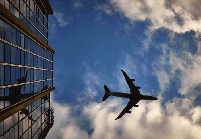 Aeroplane low in the sky reflected in building