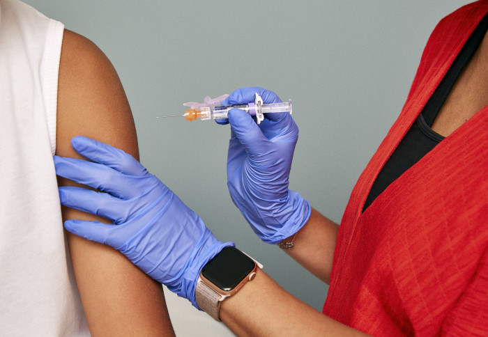 Close up of an arm and a doctor's hands holding a vaccine