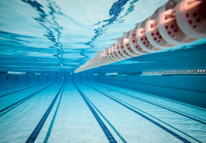 A swimming pool, underwater, with the land divider in the foreground and stretching out to the very end of the pool