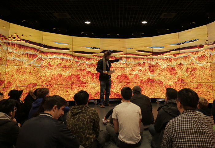 Photo of Professor Vincent speaking to an audience in front of a screen displaying flow data