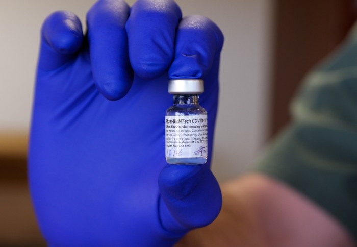 Person holding up a vial of the Pfizer/BioNTech coronavirus vaccine
