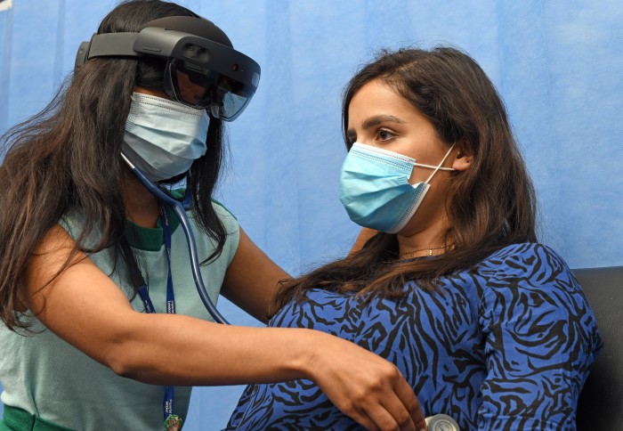 Doctor examines patient using a stethoscope while wearing the Microsoft HoloLens headset