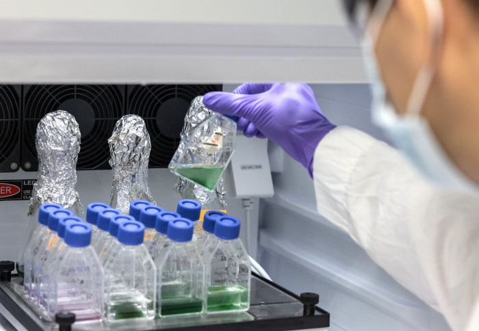 A scientist holds up a flask of green liquid