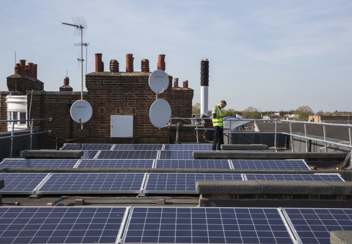 Man walking between rooftop solar panels