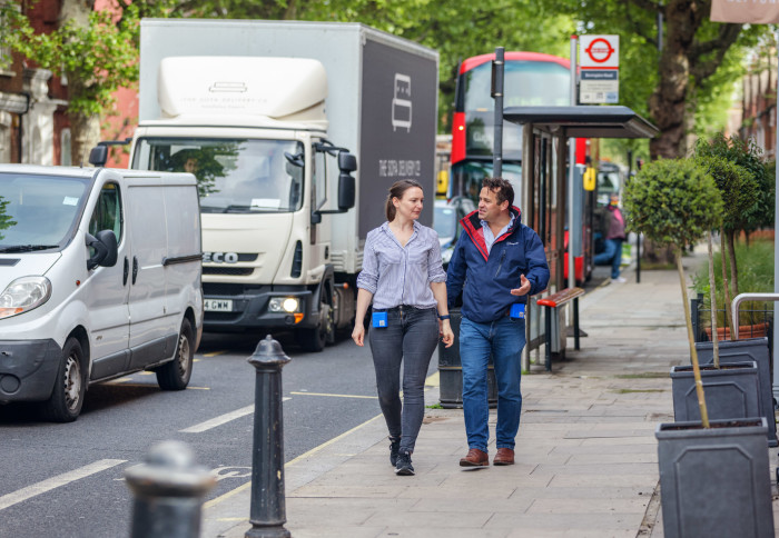 A man and woman walk down a busy road in London