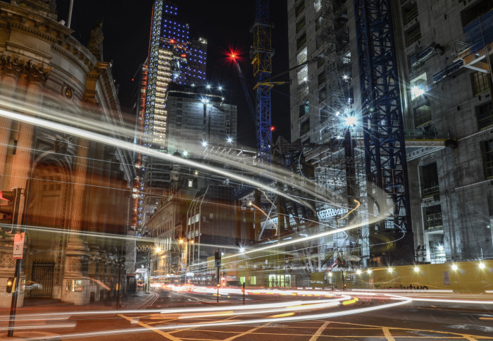 Fast moving traffic moves along London streets; the light from the headlamps of the vehicles is blurred, suggesting speed