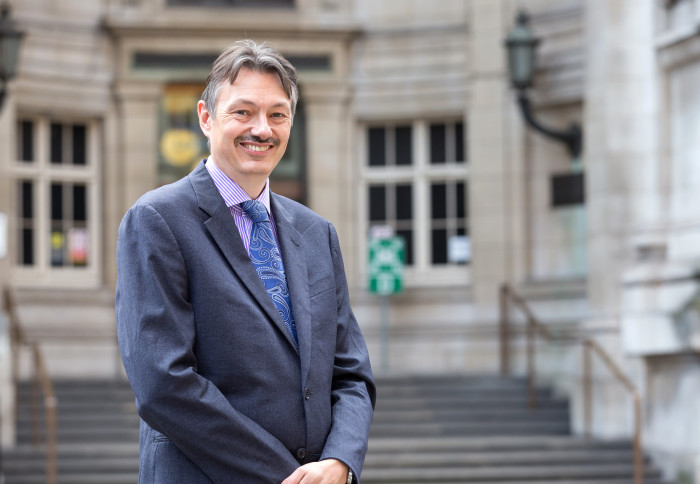 Professor Nigel Brandon standing and smiling in front of Imperial's Royal School of Mines building