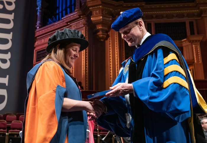Rebeca Santamaria-Fernandez being presented with a President's Medal by Professor Ian Walmsley in the Royal Albert Hall. Both are wearing academic dress.