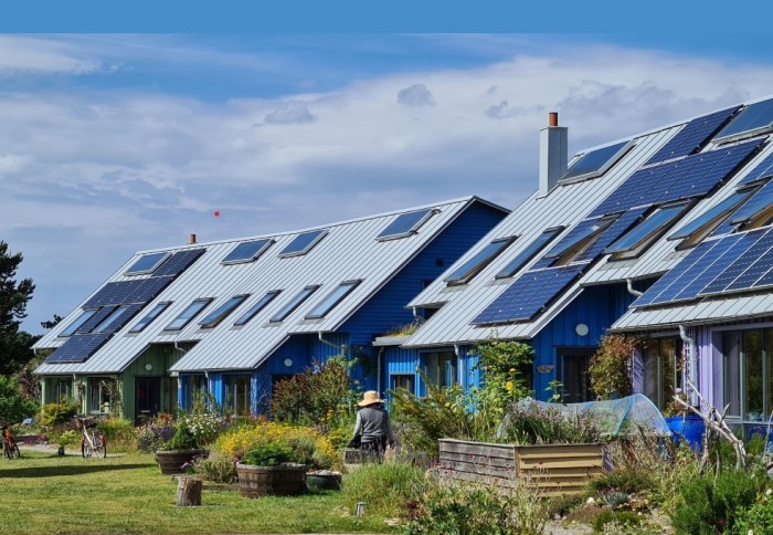 Cover image of the IPCC WGIII 6th Assessment Report, showing houses with solar panels surrounded by green gardens