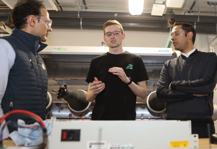 three men talk in a workshop