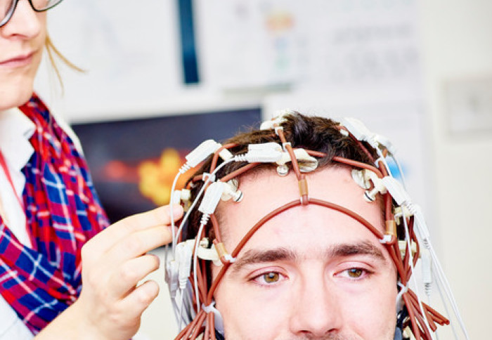 Woman fitting electrode cap to man