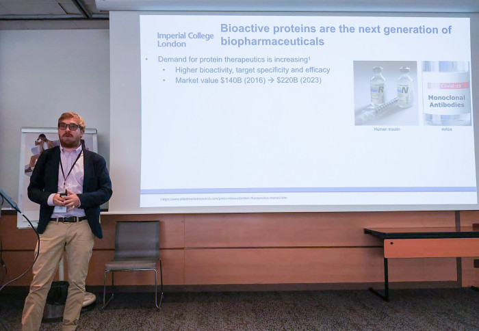 Man standing in front of a presentation screen delivering a talk