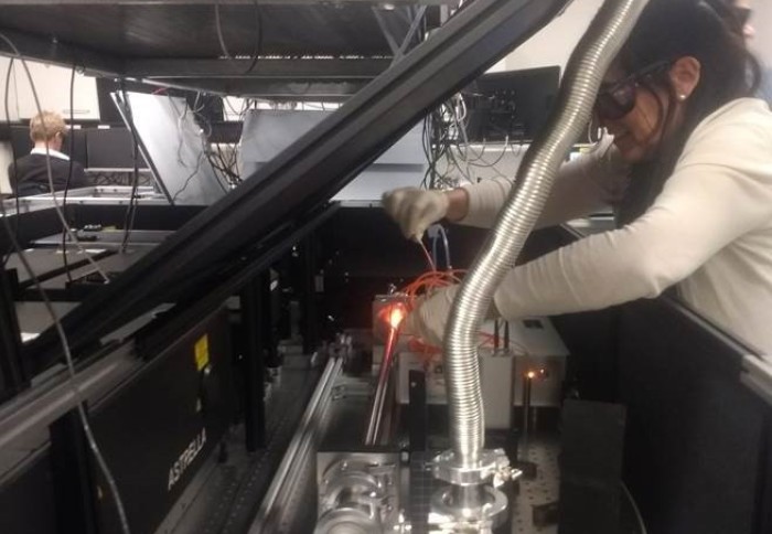 A researcher leaning into some laser equipment