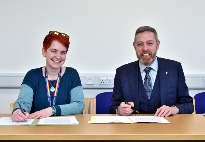 Professor Mary Ryan and RAF Air Commodore Jez Holmes sign the MOU while smiling at the camera