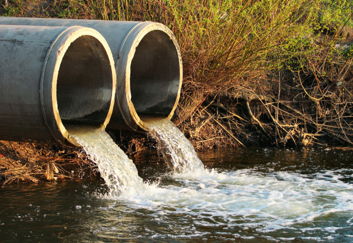 Two sewer pipes discharging water into a stream