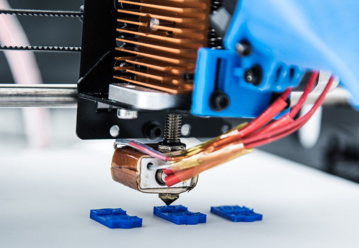 Photo of a 3D printer, putting together little blue machine parts