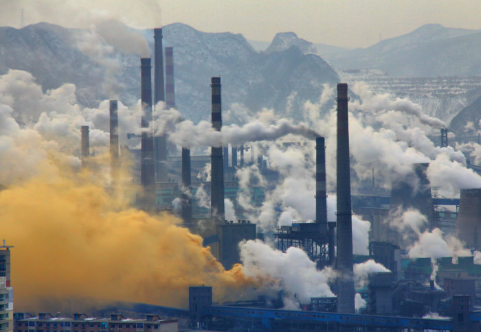 Smokestacks emitting thick white and yellow gases into the atmosphere.