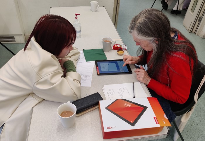 Student helping an older citizen use a tablet