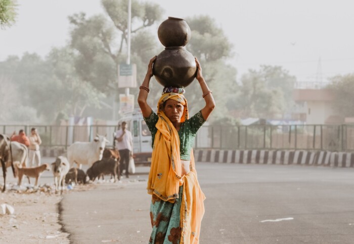 A women carries pots on her head in hot temperatures in India.