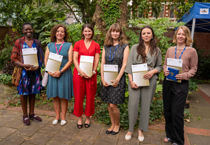 Six women standing in a line holding certificates