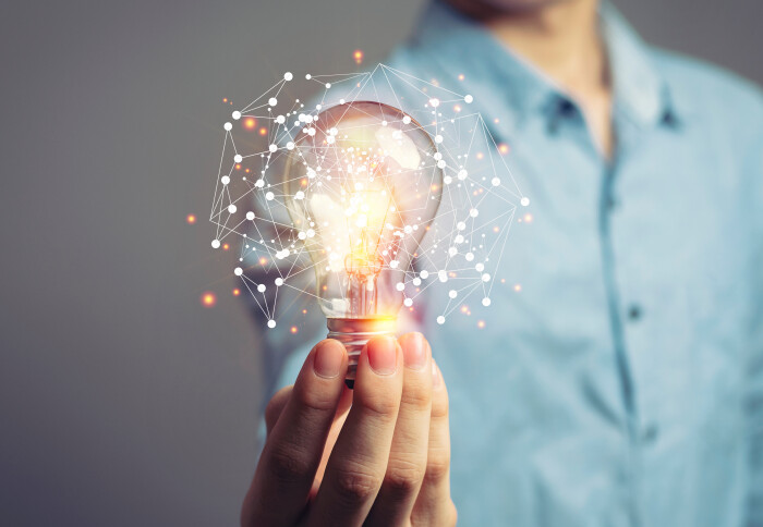 A suited person holding a lightbulb