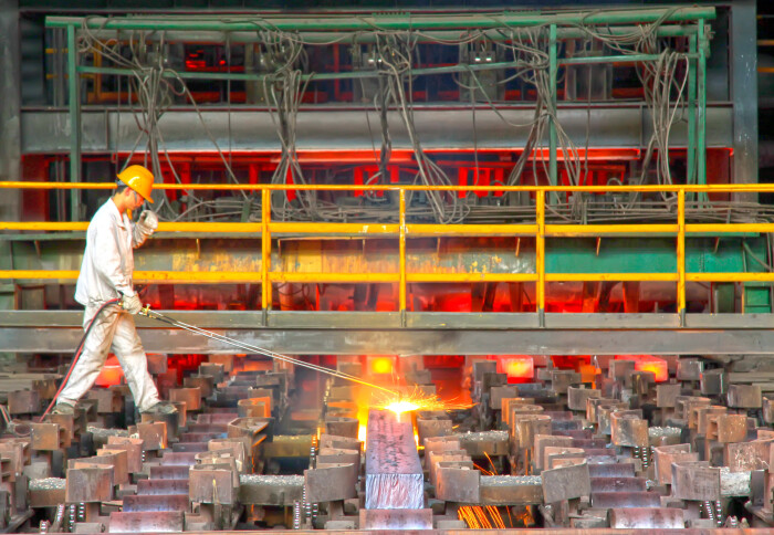 Workers cutting steel ingot behind the continuous casting machine in steel plant, on June 20, 2014, Tangshan city, Hebei Province, China