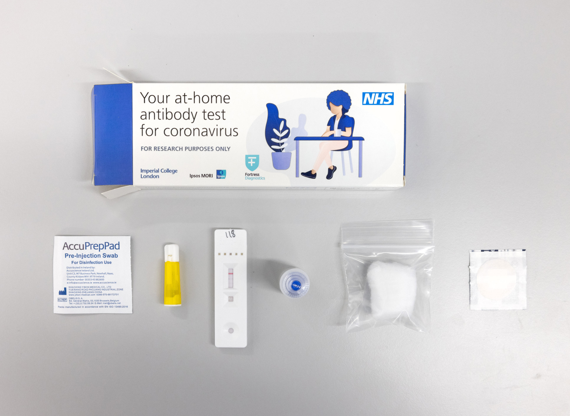 Contents of COVID-19 antibody test laid out  including swab, cotton wool and box