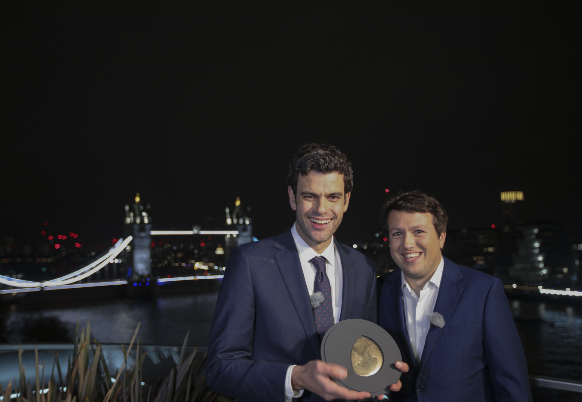 Two men stand in front of the Tower of London at night