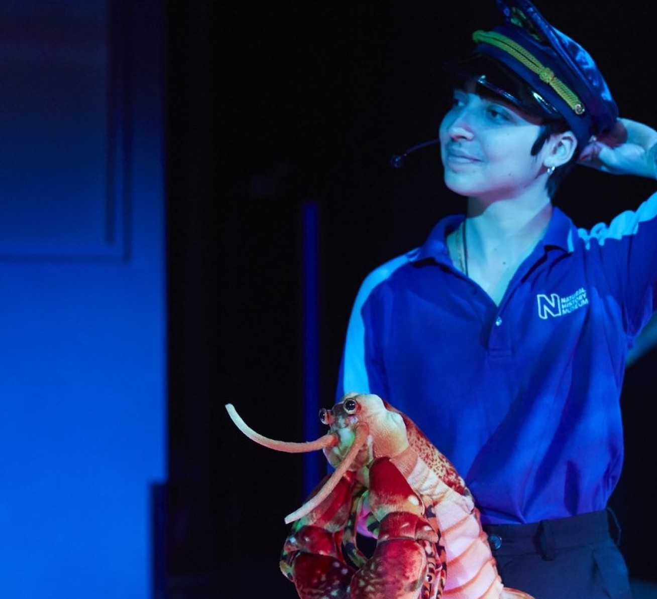 A woman with a tour guide hat holding a lobster stuffed toy