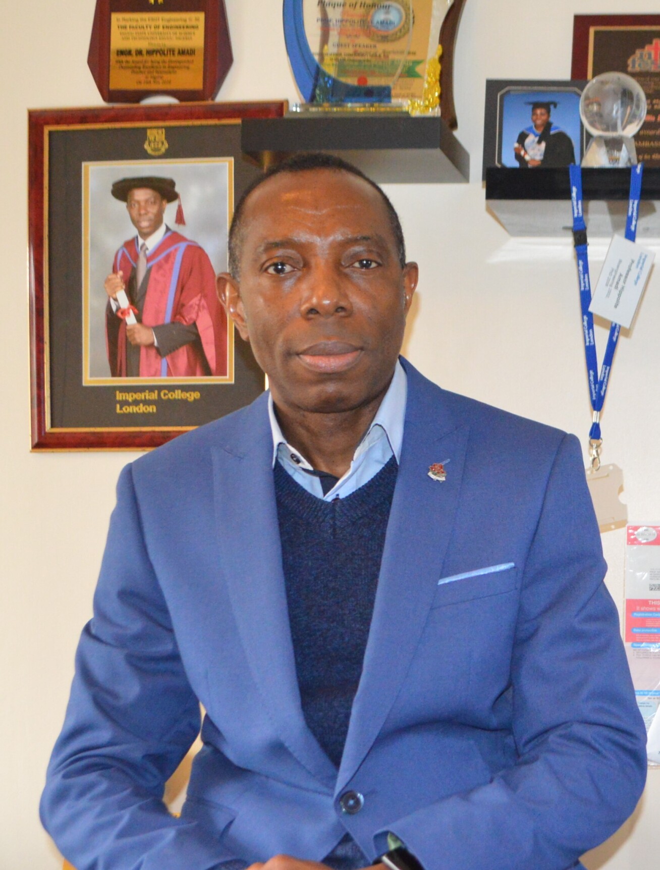 Professor Amadi wearing a blue suit sits looking at the camera