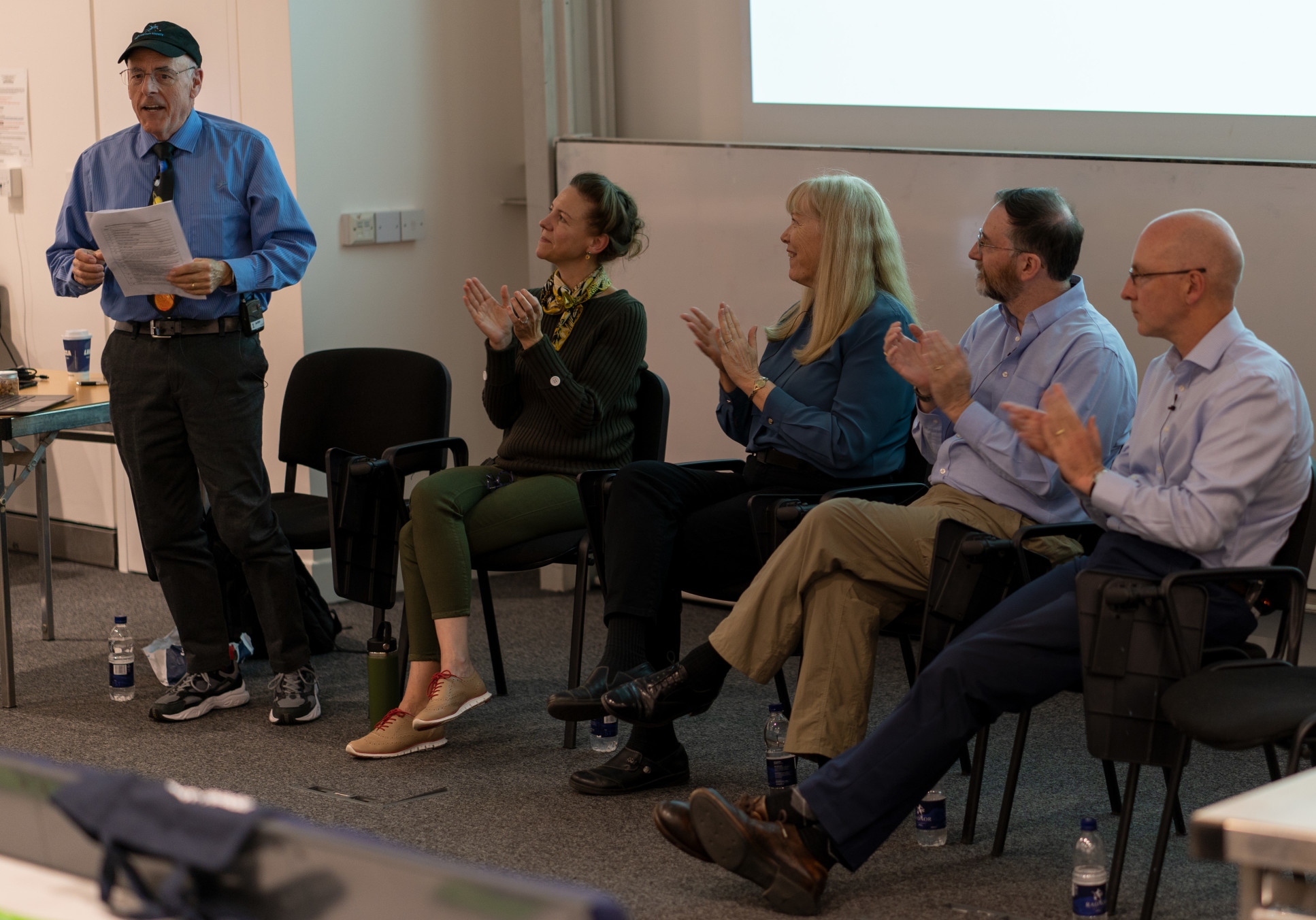 A group of panellists sit in front of an audience