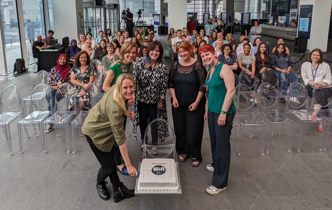 Panellists cutting a cake in front of the audience who are smiling