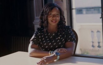 Woman sits at table and smiles 