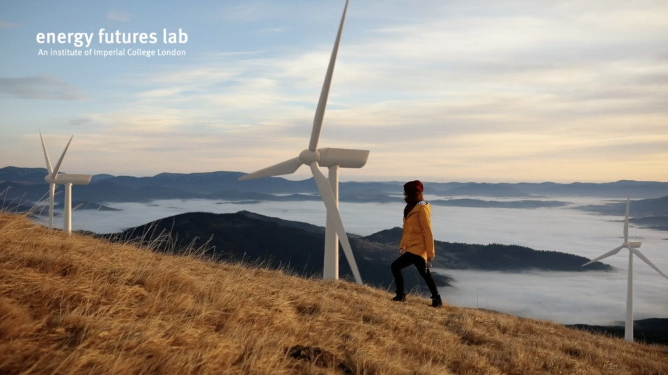 Woman climbing hill with wind turbines behind
