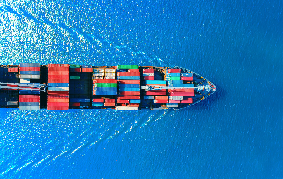 Photo from above of a ship moving through water and creating waves