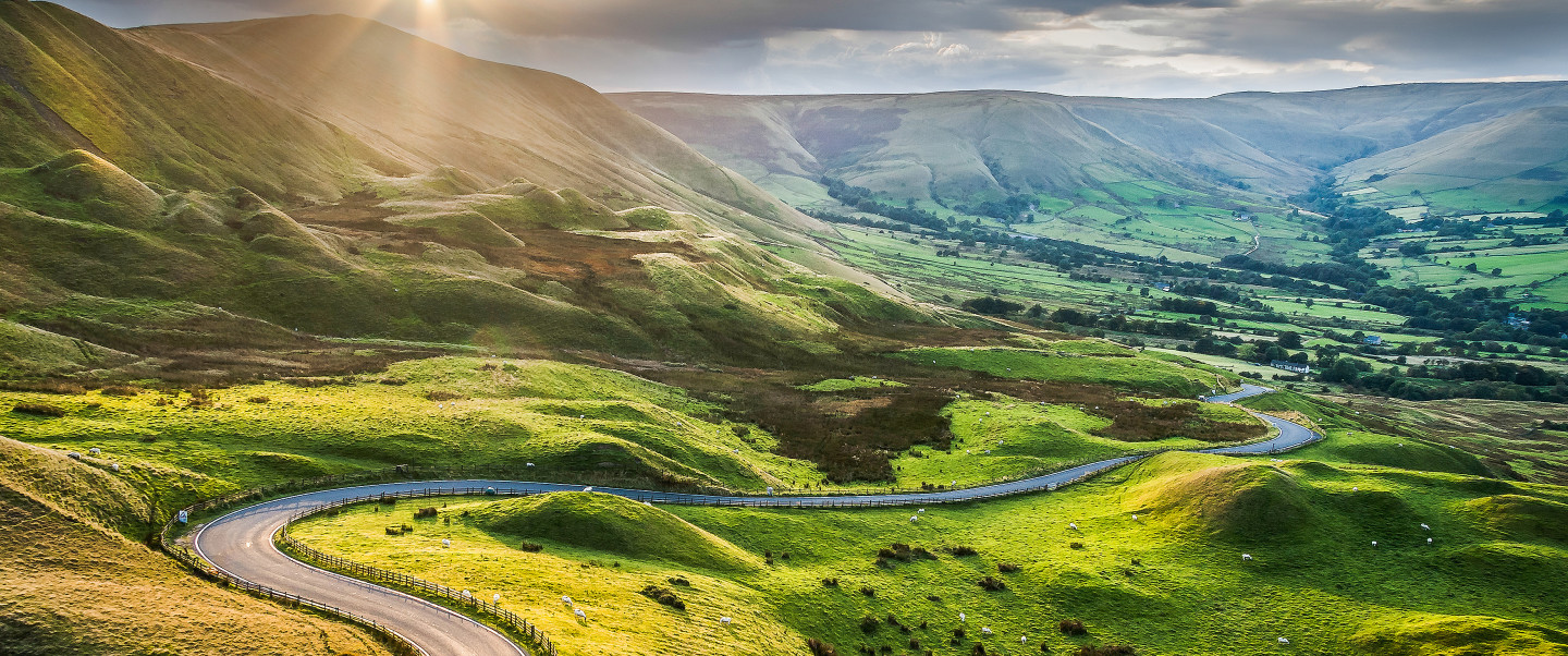 Green landscape with rolling mountains and road winding down the hills