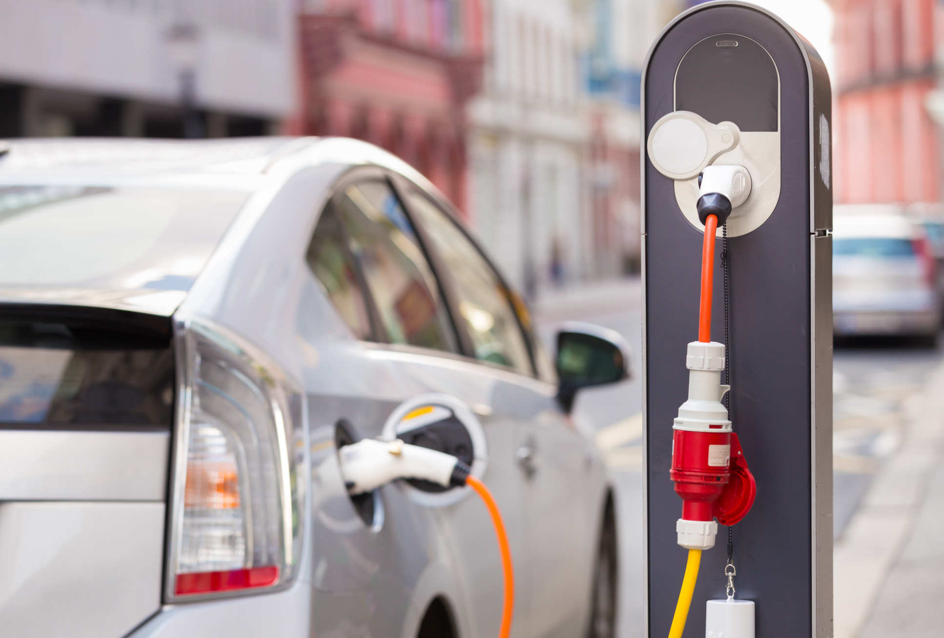 Power supply for electric car charging. Electric car charging station. Close up of the power supply plugged into an electric car being charged. 