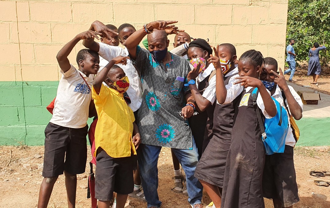 Sunday (centre) is surrounded by school children in an African rural setting