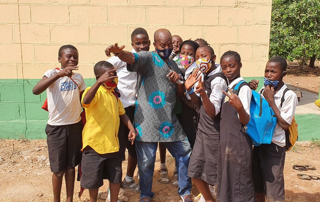 Sunday (centre) is surrounded by school children in an African rural setting