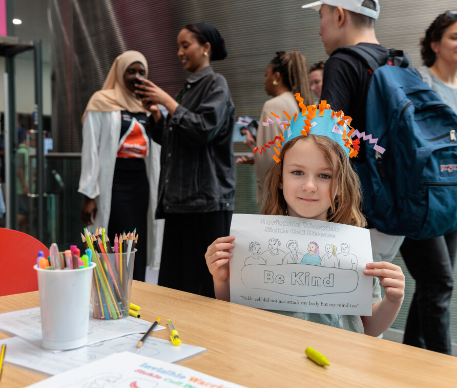 Image of a child holding up Invisible Warrior poster at the Great Exhibition Road festival 2023.