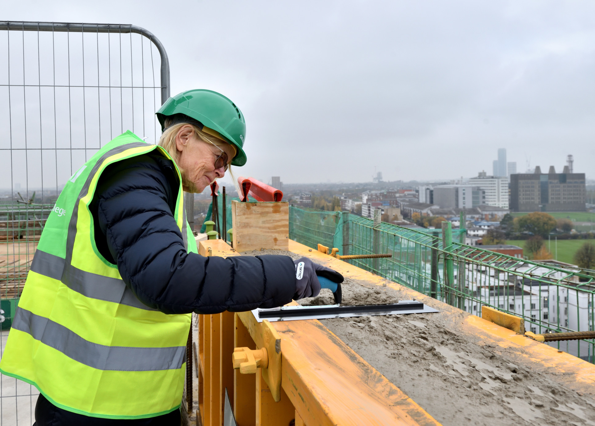 Imperial donor and alumnus Marit Mohn applies mortaring on the roof of the new School of Public Health building