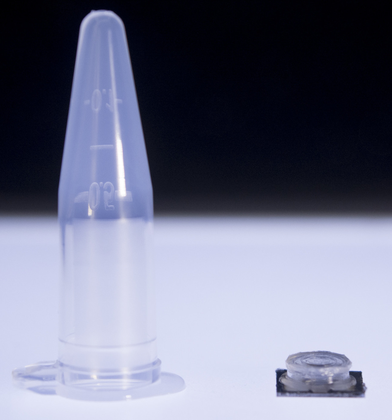 Photo of the chip next to a fluid collecting vial, demonstrating its small size