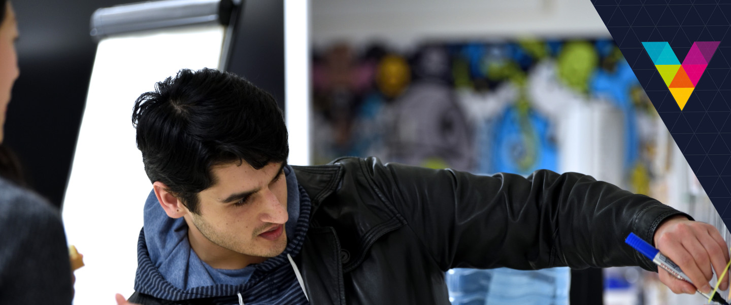 Light-skinned man writes on a sticky note on the wall