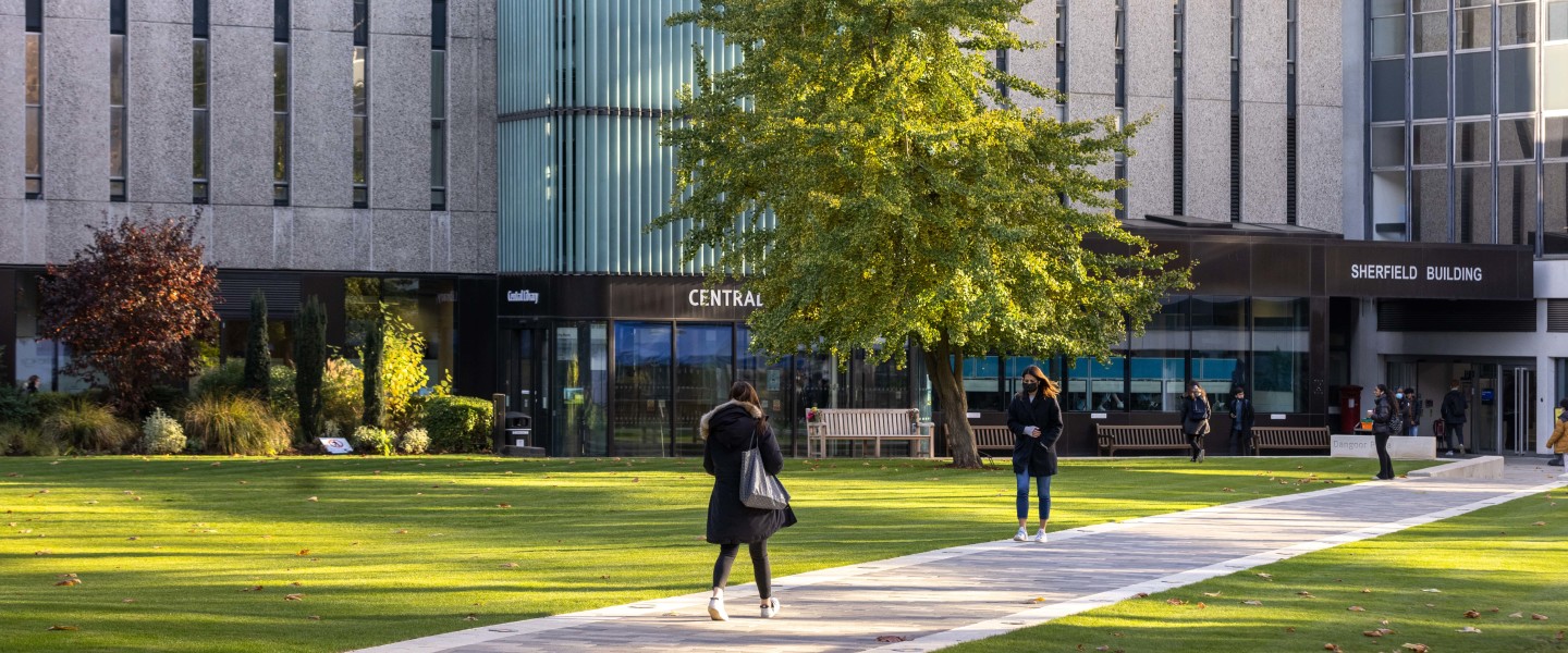 Students walk across a path on the South Kensington Campus.