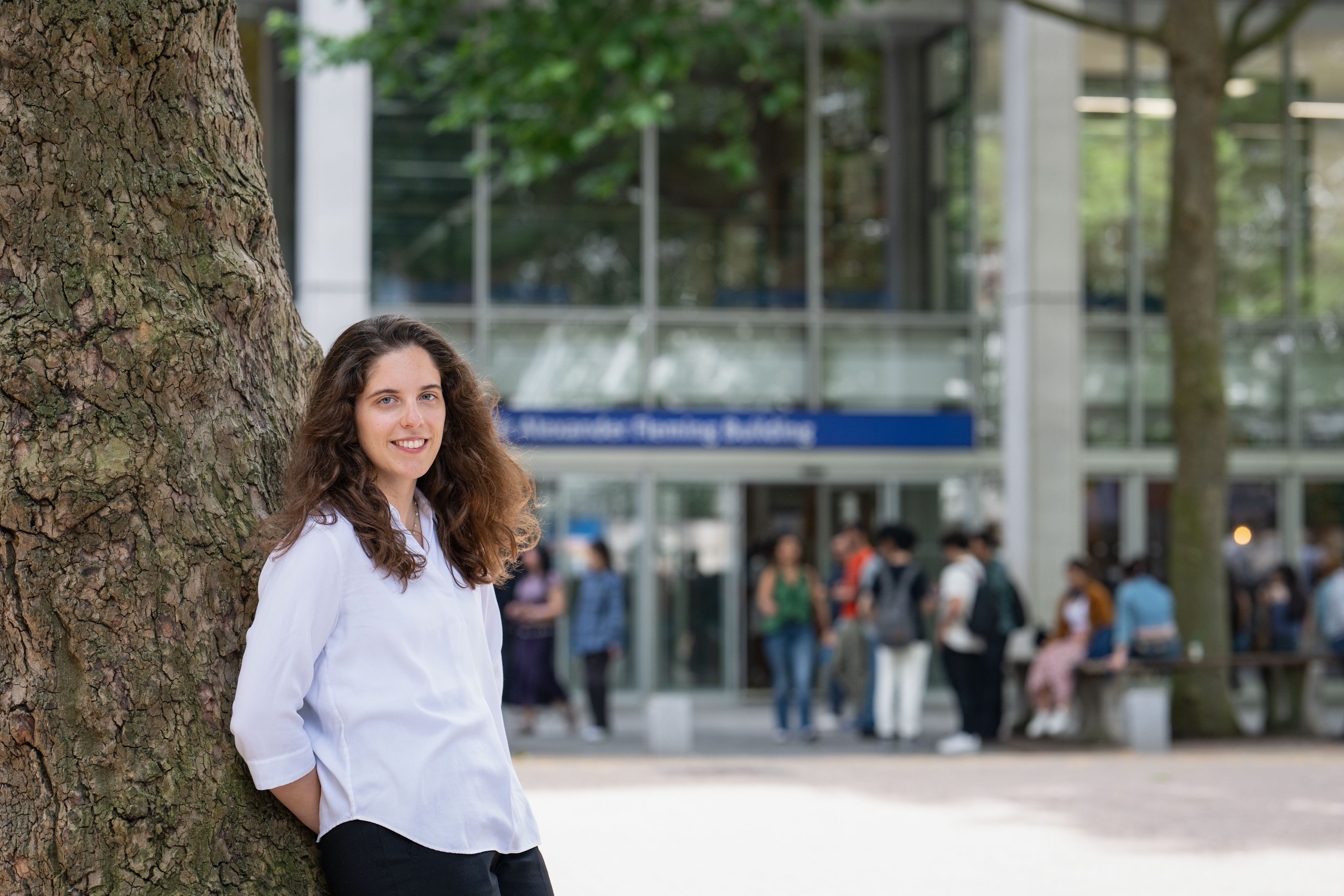 Alexandra leaning against a tree in front of the Sir Alexander Fleming building