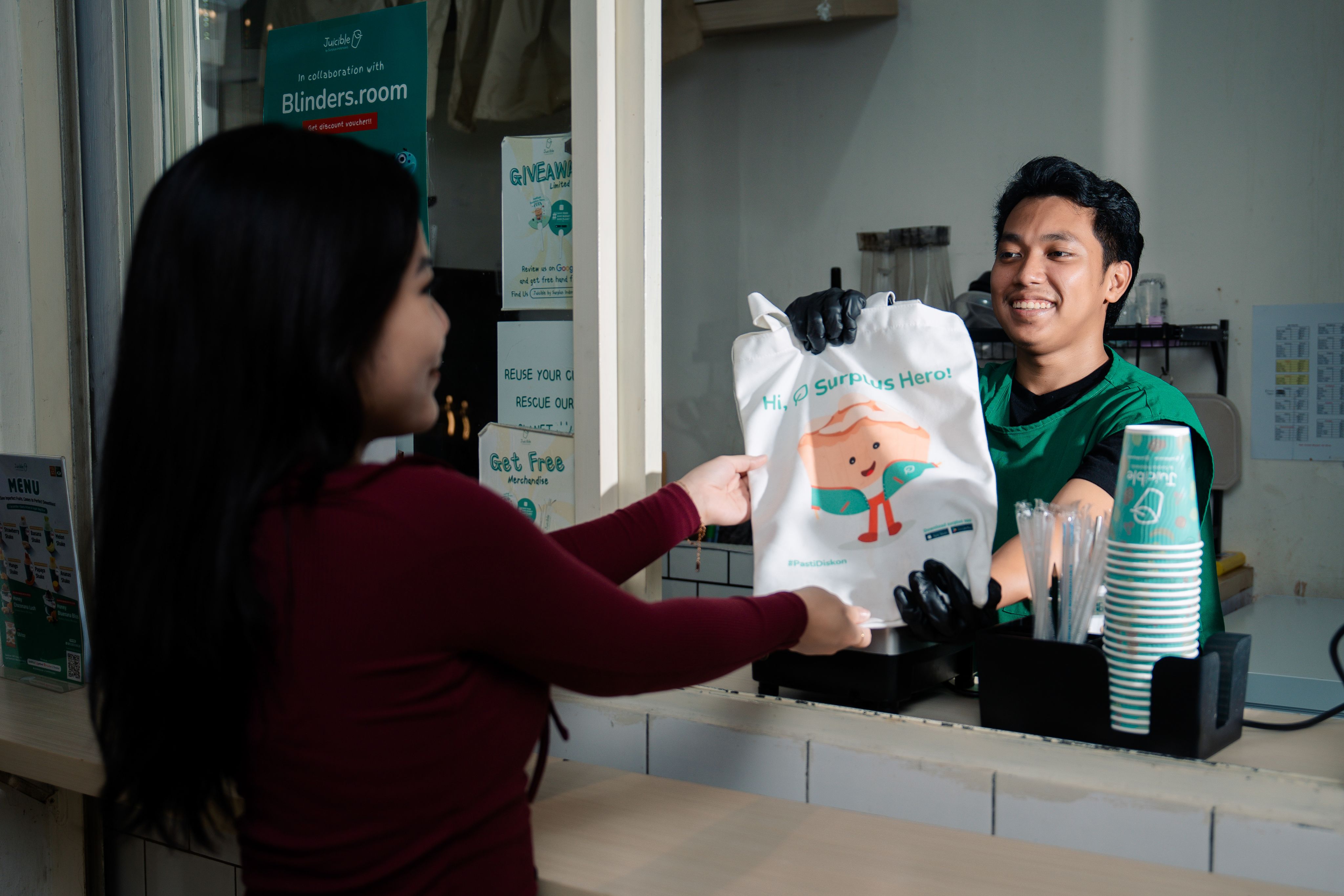 Agung Saputra handing a Surplus bag over to a customer