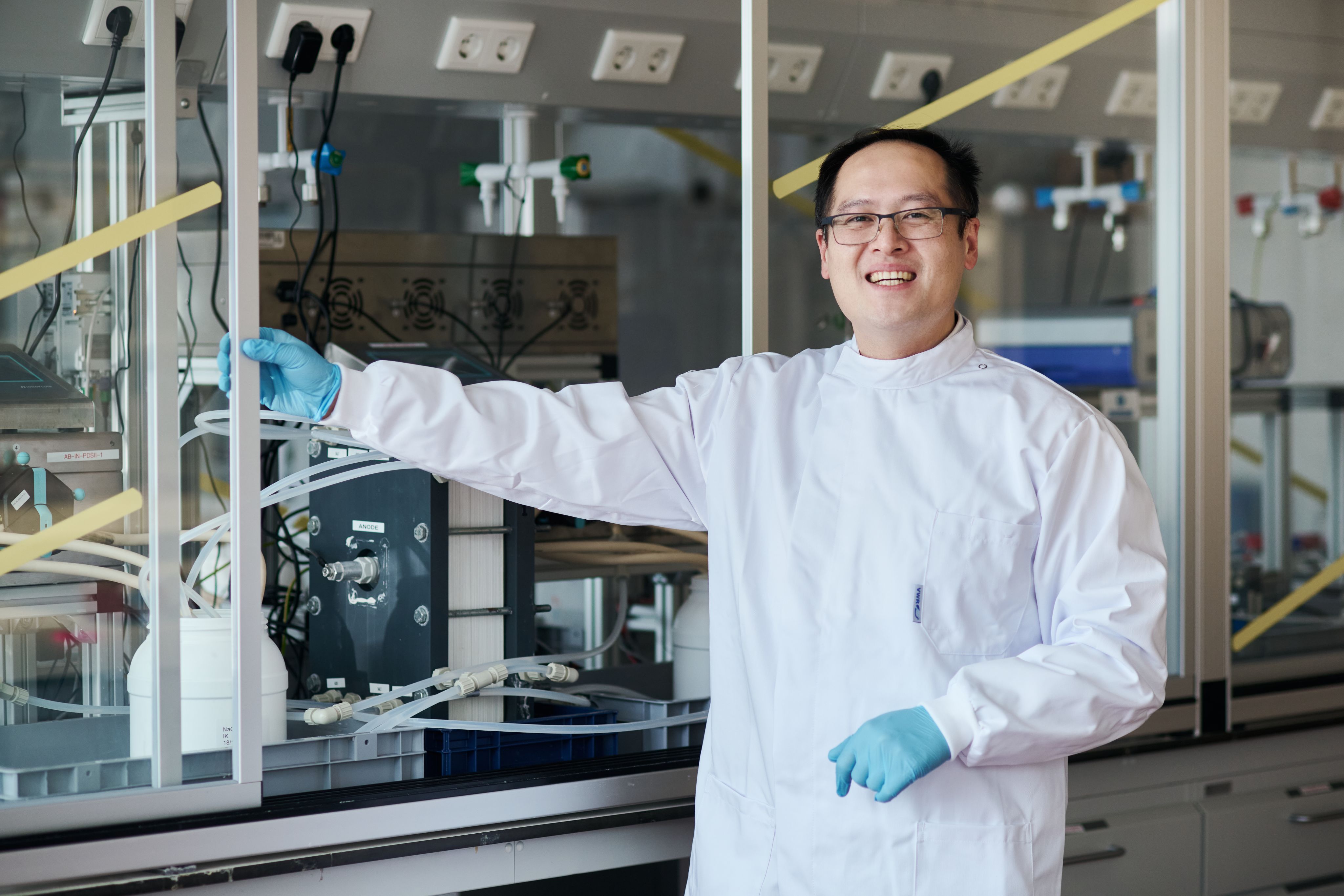 Dr Jiajun Cen wearing a lab coat in his lab smiling to camera