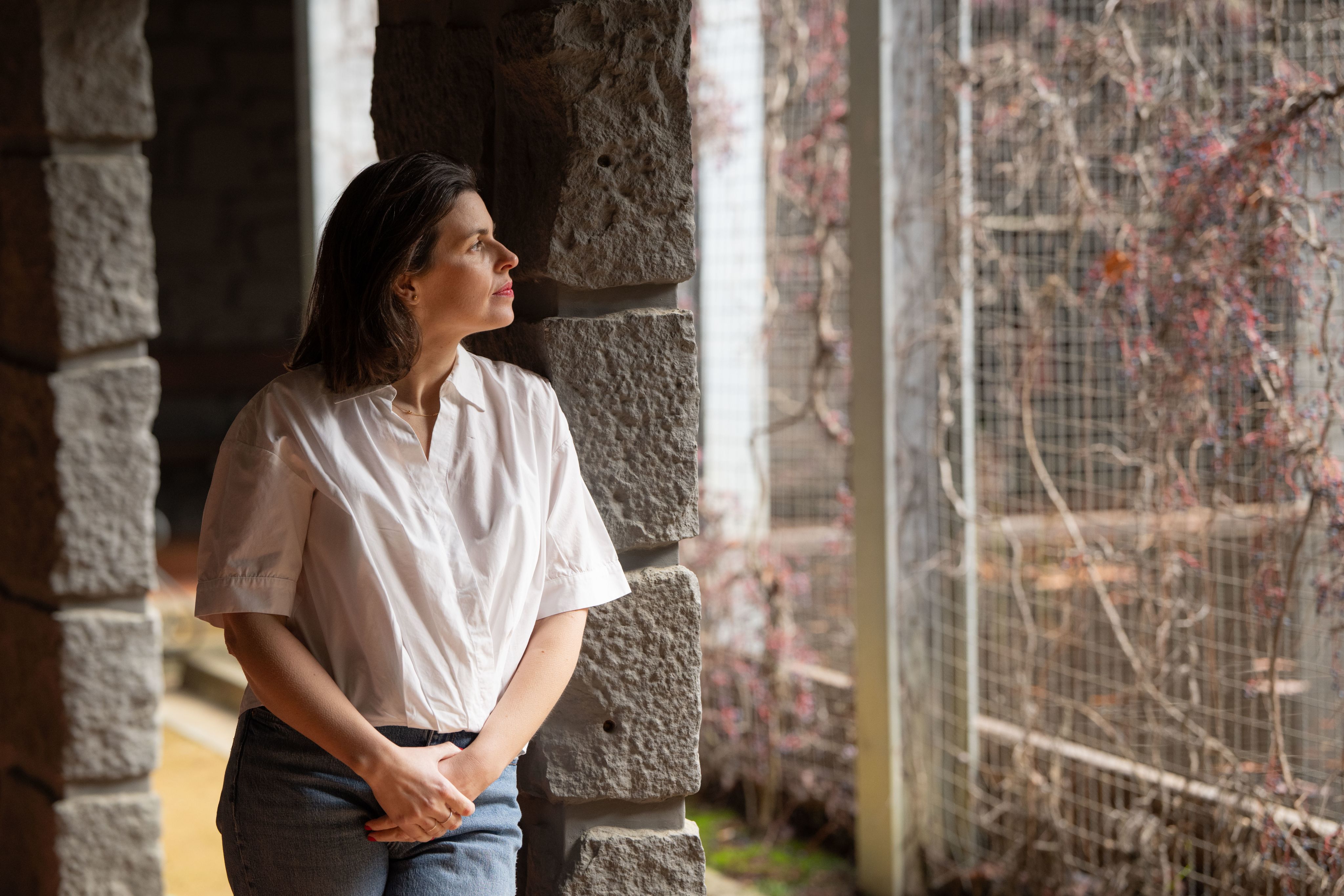 Joana Moscoso wearing a white shirt looking out of a window