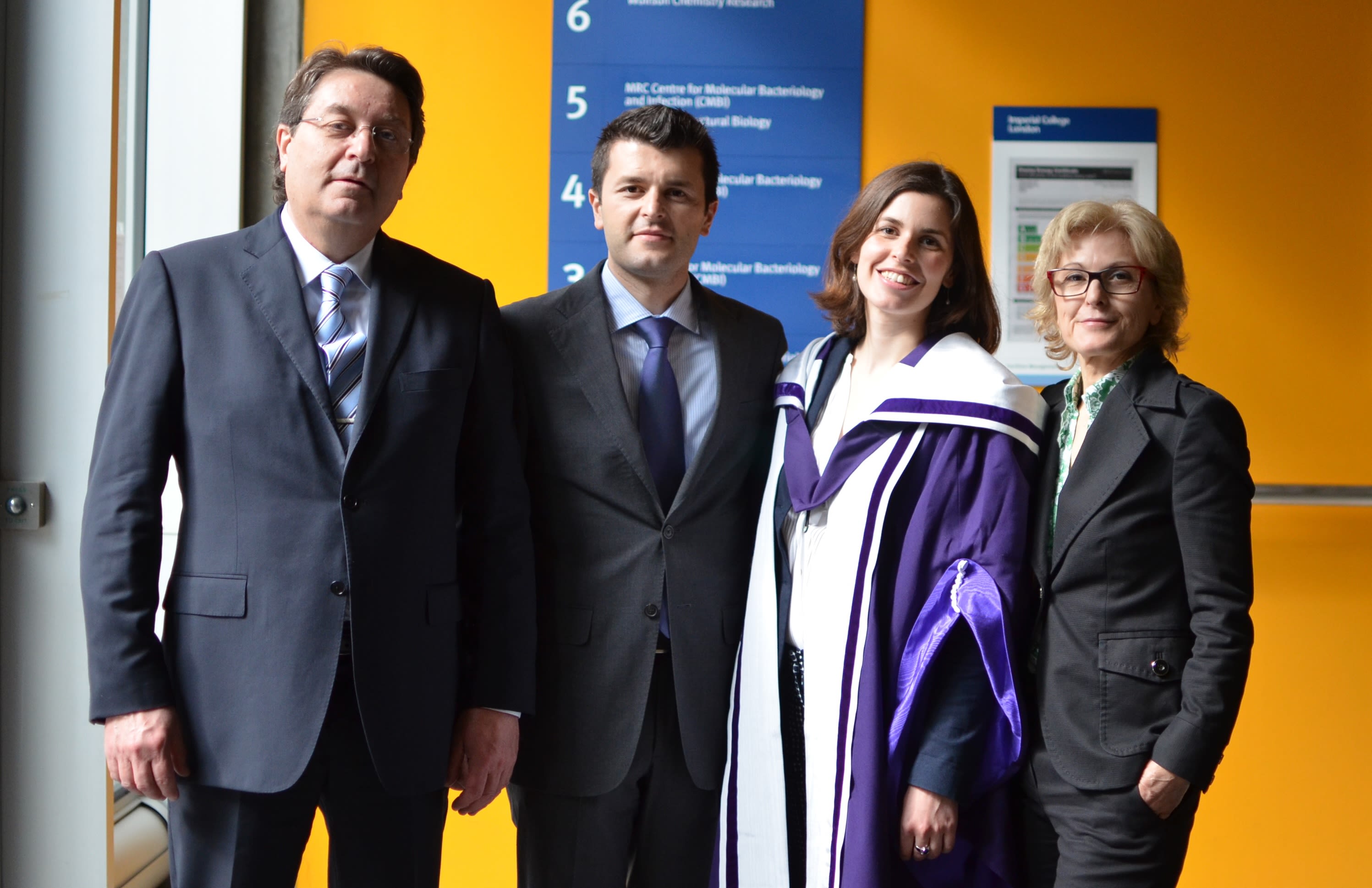 Joana wearing her graduation robes stood with 3 other people