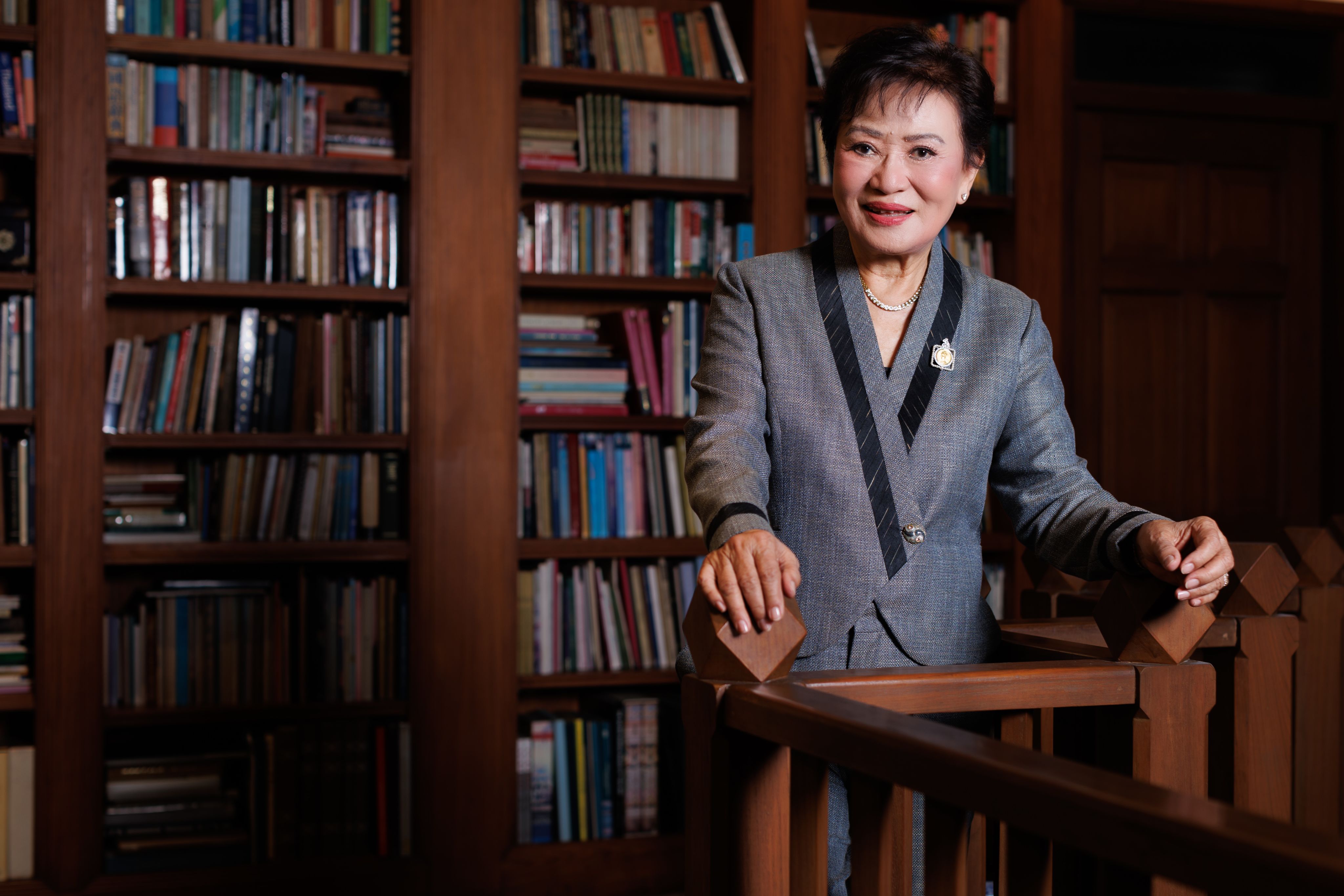 Kalaya Sophonpanich stood in front of full bookshelves made of dark wood  